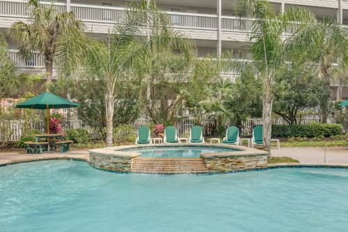 a swimming pool with chairs and a table and an umbrella at Turtley Awesome Beachfront Condo Pool in Galveston