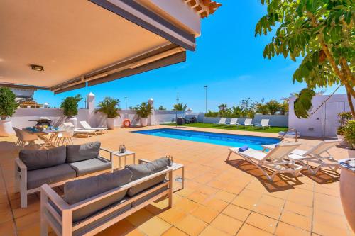 a patio with lounge chairs and a swimming pool at Espectacular Villa Aurora By Paramount Holidays in Puerto de Santiago