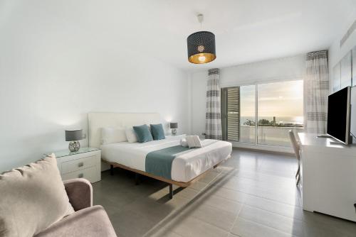 a bedroom with a bed and a couch and a television at Espectacular Villa Aurora By Paramount Holidays in Puerto de Santiago
