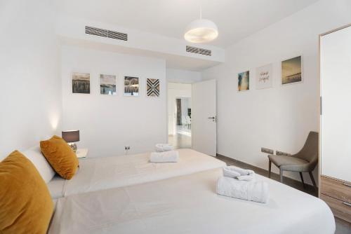a white bedroom with a large bed and a chair at Espectacular Villa Aurora By Paramount Holidays in Puerto de Santiago