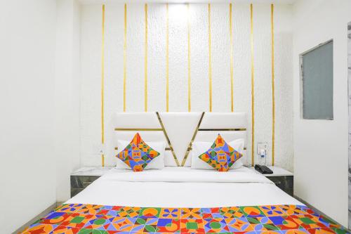 ein Schlafzimmer mit einem weißen Bett und bunten Kissen in der Unterkunft FabExpress Mahi Ganga Heritage in Haridwar