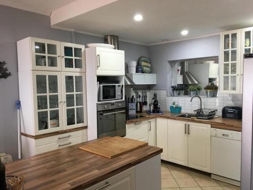 une cuisine avec des armoires blanches et un comptoir en bois dans l'établissement Front de mer cap d'agde, au Cap d'Agde