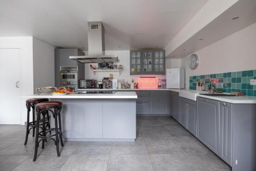 une grande cuisine avec des placards blancs et des tabourets de bar dans l'établissement L'appartement du Cirque, à Paris