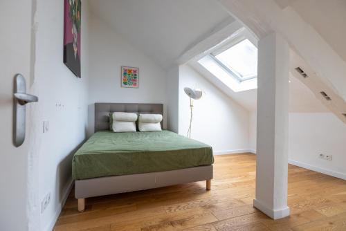 un lit dans une chambre blanche avec une fenêtre dans l'établissement L'appartement du Cirque, à Paris