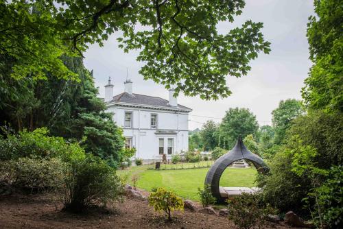 a white house with a large arch in the yard at Ballinwillin House in Mitchelstown