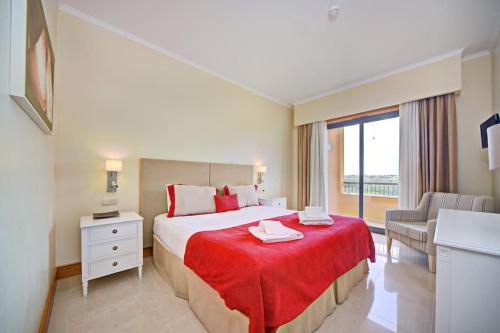 Habitación de hotel con cama con manta roja en Vilamoura Prime @ The Residences at Victoria, en Quarteira