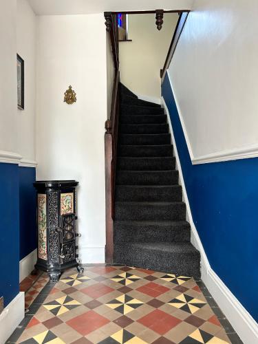 a staircase with blue walls and a checkered floor at Cadwgan House in Rhayader
