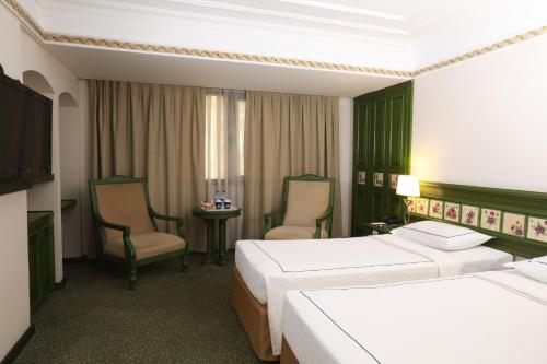 a hotel room with two beds and two chairs at Anemon Hotel Izmir in Izmir
