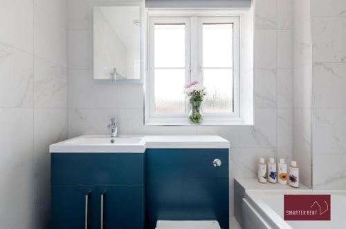 łazienka z niebieską umywalką i oknem w obiekcie Guildford - 3 Bedroom Home - Driveway & Garden w mieście Guildford
