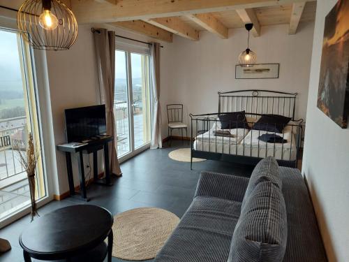 a living room with a bed and a couch at BNB Les Prises in Les Ponts-de-Martel