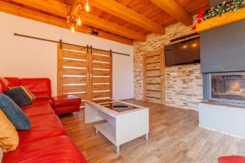 a living room with a red couch and a fireplace at Chalupa 66 - Bukovka in Červená Voda