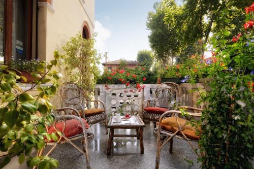 a patio with chairs and a table and flowers at Casa Villa Gardenia Venice - Atika & Atif in Marghera