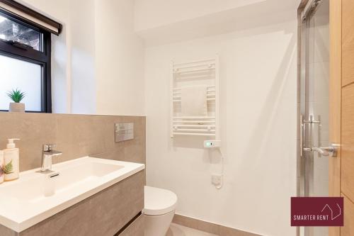 a bathroom with a white sink and a toilet at Wokingham - 2 Bedroom - Refurbished 1st Floor Flat in Wokingham