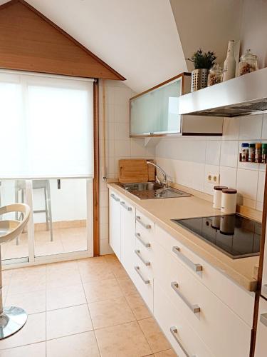 a kitchen with white cabinets and a sink and a window at Acogedor Ático en Nigran in Nigrán