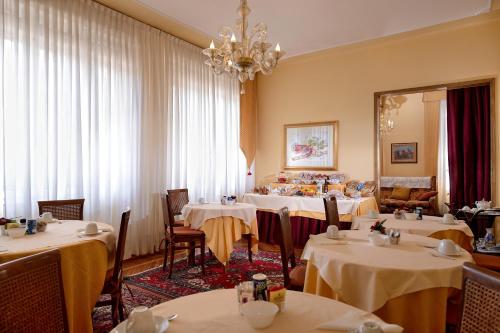 un ristorante con tavoli, sedie e lampadario a braccio di Atika & Atif - Casa Villa Gardenia Venice a Marghera