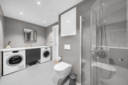 a bathroom with a washing machine and a toilet at Bjørvika - Chic apartment in Oslo center in Oslo
