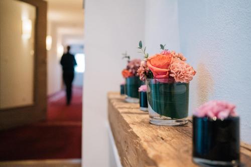 uma fila de vasos cheios de flores numa parede em Klostermaier Hotel & Restaurant em Icking