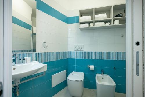 a blue and white bathroom with a toilet and a sink at Milena Suite Apartments in Alghero