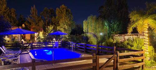 una piscina con sillas y sombrillas por la noche en Aratiri Cabañas, Un Lugar En El Bosque.. en Colón
