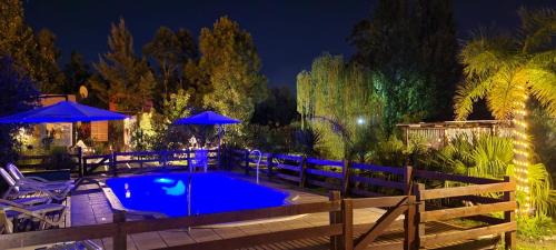 a swimming pool with chairs and umbrellas at night at Aratiri Cabañas, Un Lugar En El Bosque.. in Colón