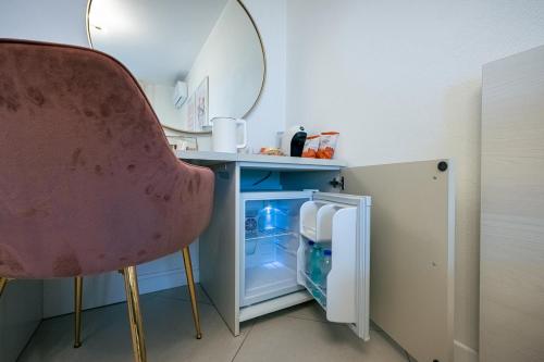 a room with a chair and an open refrigerator at Milena Suite Apartments in Alghero