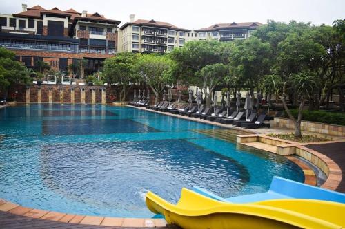a large swimming pool with chairs in a resort at Resort Retreat, Private Suite, Zimbali Estate in Ballito