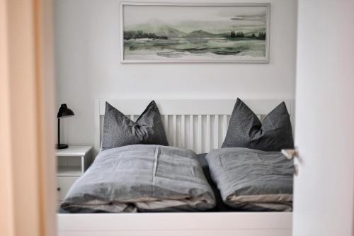 a bed with two pillows and a picture on the wall at Pößnecker Werkstätten - Martin Luther in Pößneck