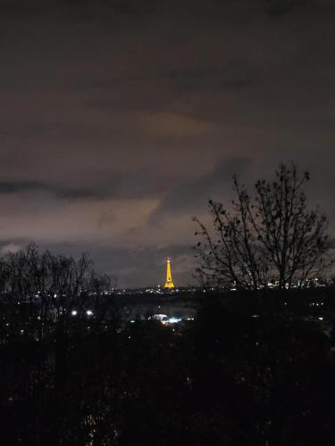 a view of the eiffel tower at night at Le Rooftop Suresnes Paris La Défense - Spacieux Duplex 100 m2 Terrasse in Suresnes