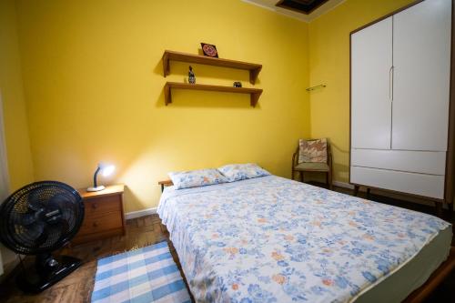 um quarto com uma cama, uma ventoinha e uma parede amarela em Casa na Serra - Cidade Imperial em Petrópolis