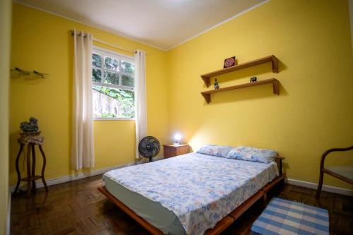 a yellow bedroom with a bed and a window at Casa na Serra - Cidade Imperial in Petrópolis