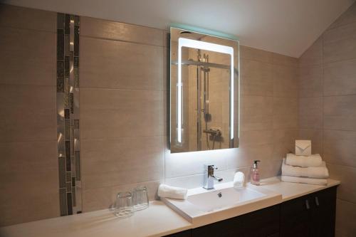 a bathroom with a sink and a mirror and a shower at Ferrypoint House in Rhu