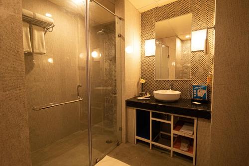 uma casa de banho com uma cabina de duche em vidro e um lavatório. em Zone by The Park Digha em Digha