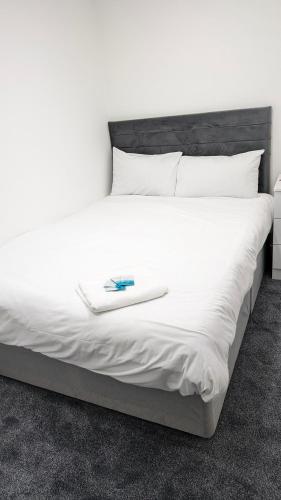 a white bed with a book on top of it at Cosy Rooms in Ilford