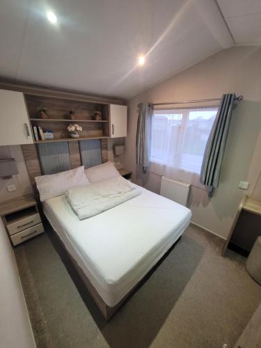 a bedroom with a white bed and a window at A22 Holiday Resort Unity Brean Passes Included Sleeps 8 people 3 bedrooms No pets in Berrow