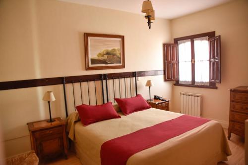 1 dormitorio con 1 cama grande y 2 almohadas rojas en Hosteria Casagrande en Tandil