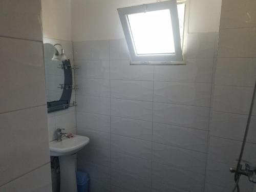 a white bathroom with a sink and a window at Hotel Flora in Çorovodë