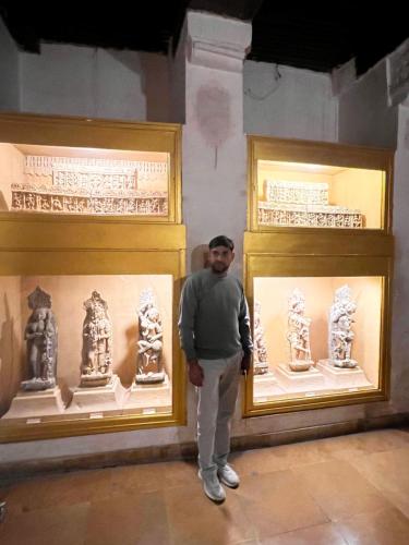 a man standing in front of two display cases in a museum at Hotel Grey Sky in New Delhi