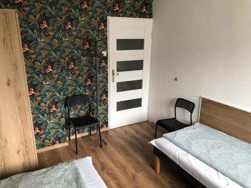 a bedroom with a bed and two chairs and a wallpaper at Noclegi na Sudeckim in Świebodzice