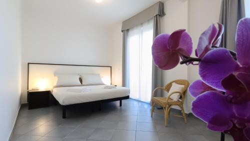 ein Schlafzimmer mit einem Bett und lila Orchideen in der Unterkunft LIDO Rooms and Apartments in Lido di Fermo