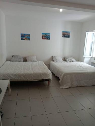 Duas camas num quarto com paredes brancas em T1 Vieux Port Opéra em Marselha