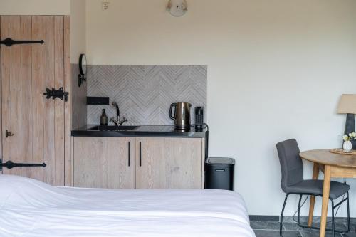 a bedroom with a bed and a sink and a table at De Vrijheid-Plantage in De Cocksdorp