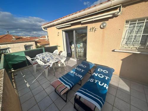 een patio met een tafel en stoelen op een balkon bij Studio en résidence WIFI VALRAS-PLAGE in Valras-Plage