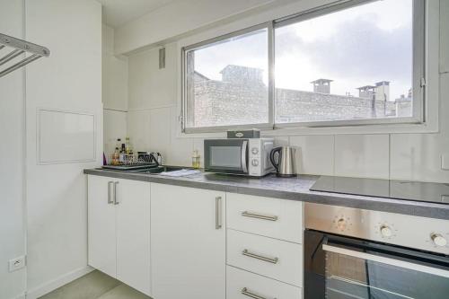 une cuisine blanche avec un four micro-ondes et une fenêtre dans l'établissement Apartment 4 Pers. Moulin Rouge-Pigalle, à Paris