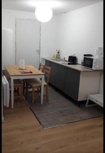 eine Küche mit einem Tisch und einer Theke mit einer Mikrowelle in der Unterkunft La casa del noche in Amiens