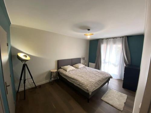 - une chambre avec un lit avec un tripod et une fenêtre dans l'établissement Appartement Chaleureux à La Madeleine - 2 Chambres, à La Madeleine