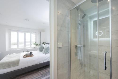 a bedroom with a shower and a bed and a glass door at Beachview Apartment 4, Crantock, Newquay in Crantock