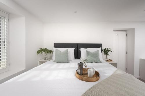 a white bedroom with a large bed with white sheets and pillows at Beachview Apartment 5, Crantock, Newquay in Crantock