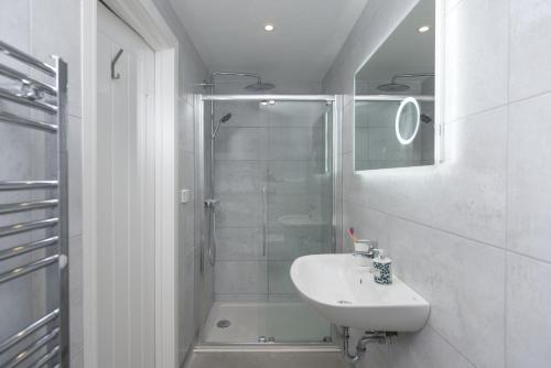 a white bathroom with a sink and a shower at Beachview Apartment 5, Crantock, Newquay in Crantock