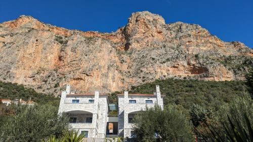a large building in front of a mountain at Sabaton Apartment - Kyziridi House in Leonidion