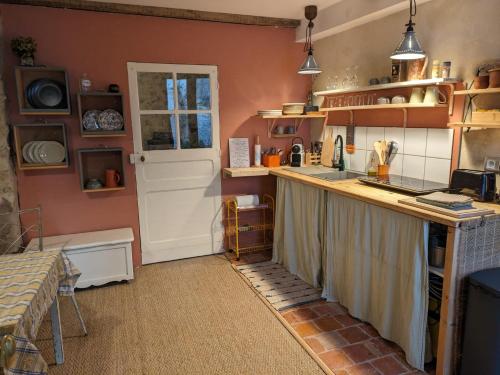 - une cuisine avec un comptoir, un évier et une porte dans l'établissement Au bois radieux - option massage, à Bellême